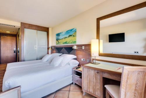 a bedroom with a bed and a desk and a mirror at Occidental Playa de Palma in Playa de Palma