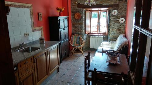 a kitchen with a sink and a table and a window at Apartamentos Los Castros in San Tirso de Abres