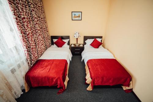 two beds in a hotel room with red pillows at Bek Khiva Hotel in Khiva