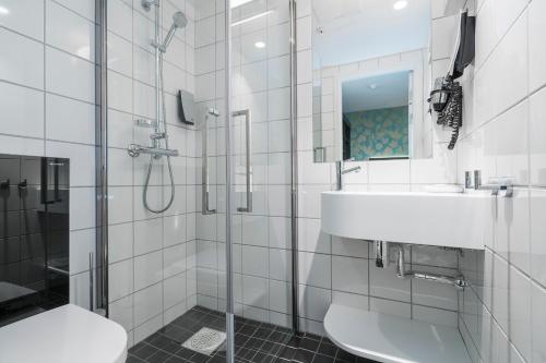 a white bathroom with a sink and a shower at Thon Hotel Nidaros in Trondheim
