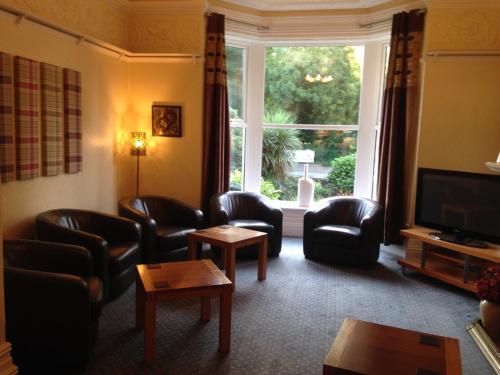 a living room with leather chairs and a large window at Rostrevor Hotel - Guest House in Bury