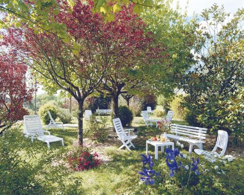 a group of white chairs and a bench in a garden at Hôtel Restaurant du Château in Rocamadour