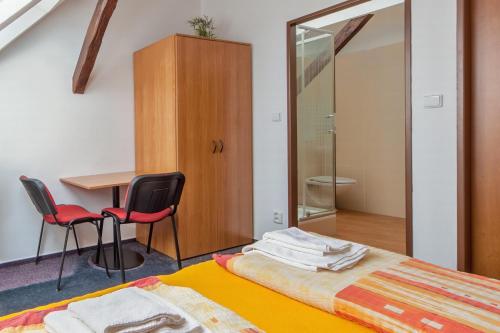 1 Schlafzimmer mit einem Bett, 2 Stühlen und einem Tisch in der Unterkunft Penzion Šalamoun in Jaispitz