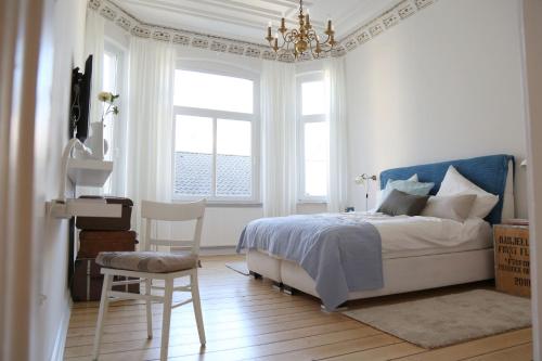 a bedroom with a bed and a chair and a chandelier at Die schöne Auguste in Oldenburg