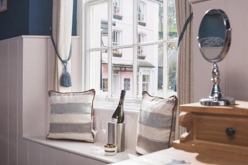 a window sill with a bottle of wine and a mirror at Havener's in Fowey