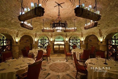 a restaurant with white tables and chairs and a chandelier at Halasi Pince Panzió in Villány