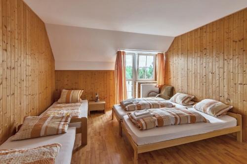 two beds in a room with wooden walls at Penzion Šalamoun in Jevišovice