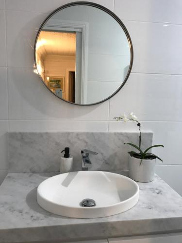 a bathroom sink with a round mirror above it at Drayshed cottage in Blayney
