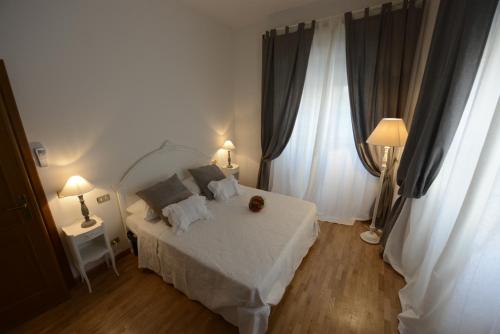 a bedroom with a white bed and two windows at Appartamento Irene in Pisa