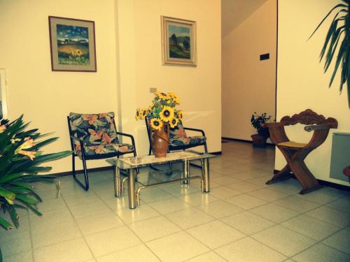 a room with two chairs and a table and a vase with flowers at Hotel Primavera in Barberino di Val dʼElsa