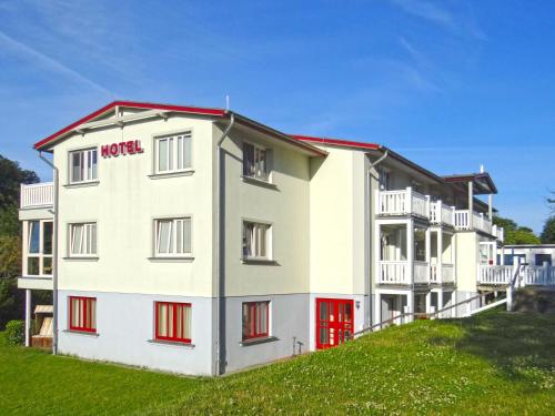 a white building with red doors on a hill at Hotel Pension Bellevue in Bad Doberan