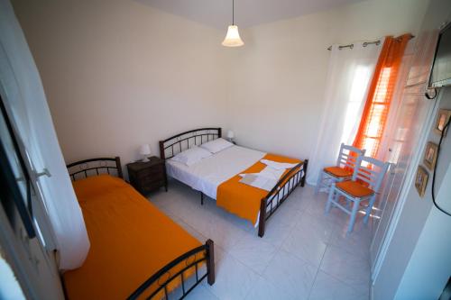 a bedroom with two beds and a table and a chair at Theodora in Panormos