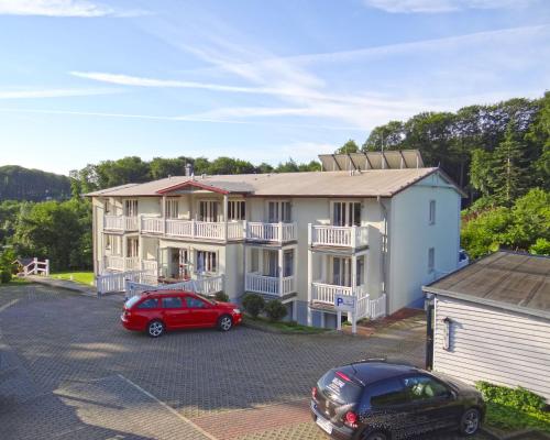 a large white house with a red car parked in a parking lot at Hotel Pension Bellevue in Bad Doberan