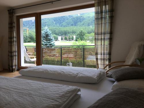 2 Betten in einem Schlafzimmer mit einem großen Fenster in der Unterkunft Apartment Plan Corones in Bruneck