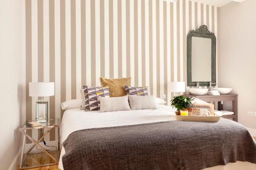 una camera da letto con un letto con pareti a righe e uno specchio di Casa Malasaña a Madrid