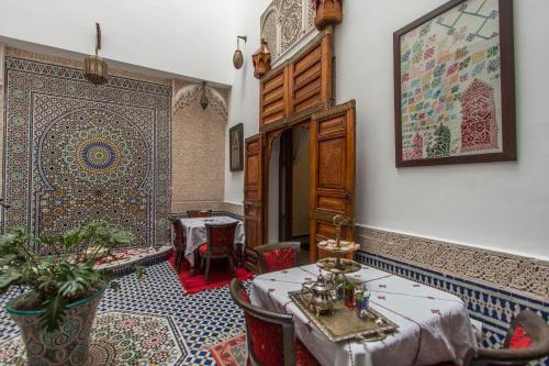 a dining room with two tables and a rug at Dar Fes Medina Ziat in Fez