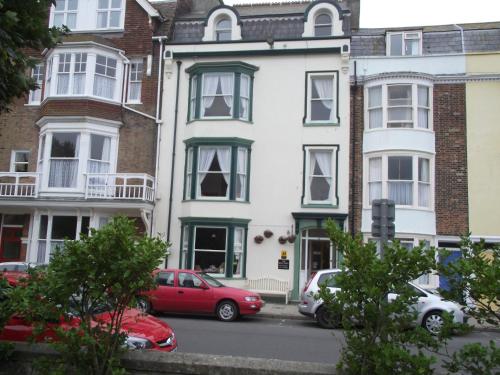 a white house with cars parked in front of it at beaufort guesthouse in Weymouth