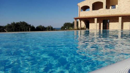 a swimming pool with blue water in front of a building at B&B CasalFarano in Cupra Marittima