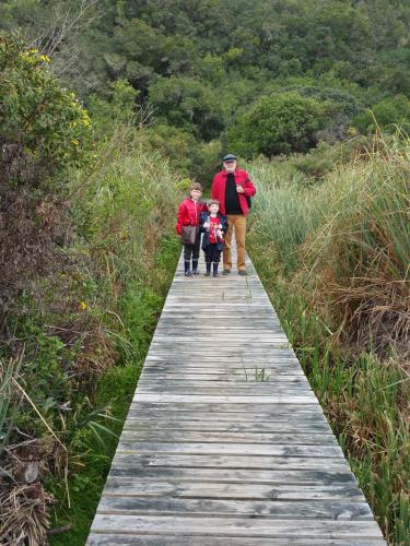 a man and two children walking down a wooden path at Serendipity Country House & Restaurant in Wilderness