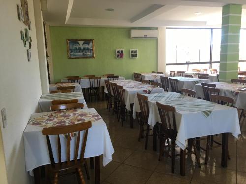 a dining room with tables and chairs with white tablecloths at Hotel Mares do Sul in Tramandaí