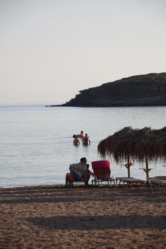 a man sitting in a chair on a beach at Elina Apartments in Batsi
