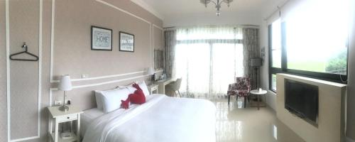 a bedroom with a white bed with red pillows and a television at 旅人空間The Cube Inn Homestay本民宿未與Agod a合作 We are not partnered with Agod a in Dongshan