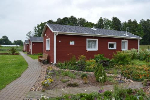 a red house with a garden in front of it at Guest House Kalnu pūpoli in Šengeida