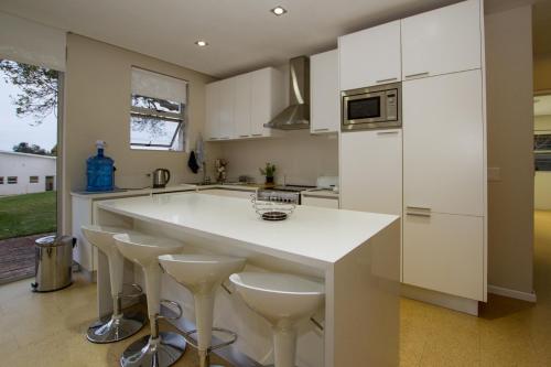 a kitchen with a large white island with stools at No1 Sangaree in Plettenberg Bay