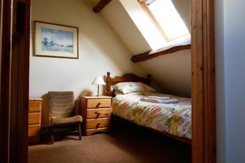 ein Schlafzimmer mit einem Bett, einem Fenster und einem Stuhl in der Unterkunft Barn Cottage in Brecon