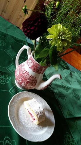 a piece of cake on a plate next to a tea pot at Ferienhof Kampfl in Fügen