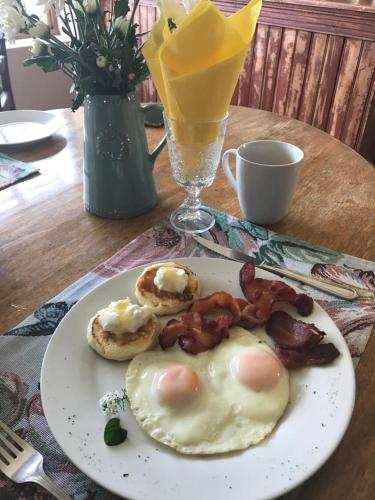 Un plato de desayuno con huevos, tocino y galletas. en Tuscana Villa Guesthouse, en Kroonstad