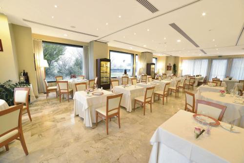 a restaurant with white tables and chairs and windows at Best Western Park Hotel in Piacenza