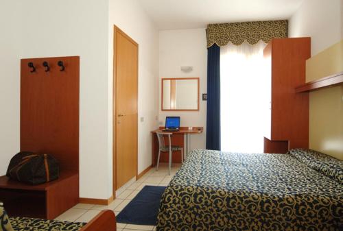 a bedroom with a bed and a desk with a laptop at Hotel Lido in Lido di Jesolo