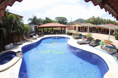 a large swimming pool with chairs and a resort at Hotel Doña Marta in Nicoya