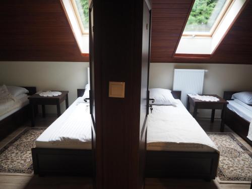 2 Betten in einem kleinen Zimmer mit 2 Fenstern in der Unterkunft Willa Zacisze - Apartament dwupoziomowy in Kalwaria Zebrzydowska