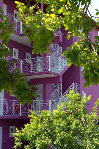 a purple building with white balconies and trees at Ideal House in Parga