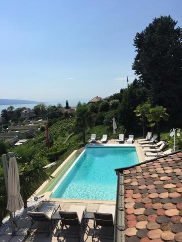 uma piscina com cadeiras e guarda-sóis em B&B Corseaux Beach & Riviera Beach em Vevey