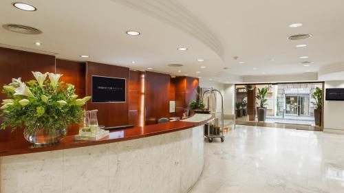 a lobby with a reception counter with a vase of flowers at Aparthotel Mariano Cubi Barcelona in Barcelona