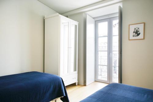 a bedroom with a blue bed and a window at Boavista Apartment (Mercado da Ribeira) in Lisbon