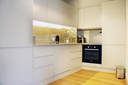a kitchen with white cabinets and a black appliance at Boavista Apartment (Mercado da Ribeira) in Lisbon