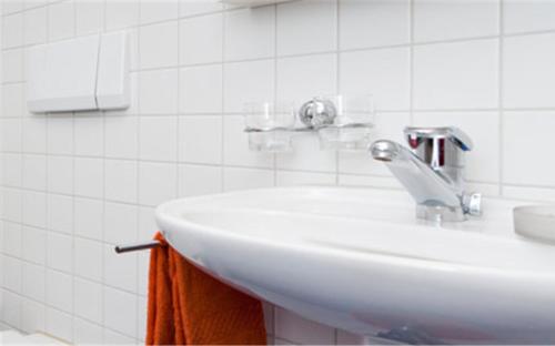 - un lavabo blanc dans la salle de bains carrelée dans l'établissement Falken am Rotsee, à Lucerne