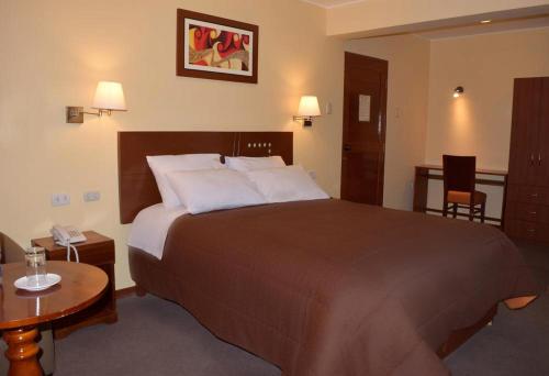 een hotelkamer met een groot bed en een tafel bij Illariy Hotel in Huancavelica