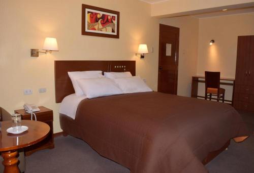 a hotel room with a large bed and a table at Illariy Hotel in Huancavelica