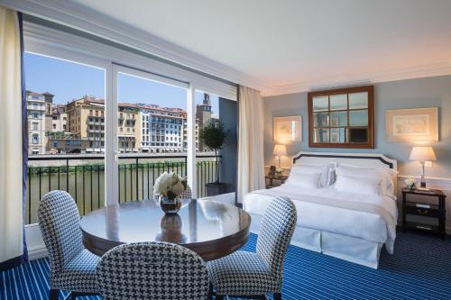 フィレンツェにあるホテル ルンガルノ ルンガルノ コレクションのベッド、テーブル、椅子が備わるホテルルームです。