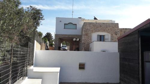 a house with a white fence and a building at La stanza del paradiso in Torre Pali 