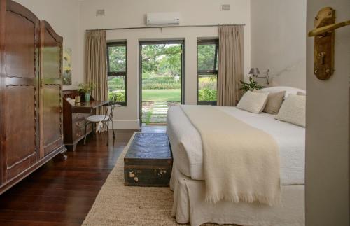 una camera con letto, scrivania e finestre di Torburnlea Homestead Luxury Accommodation a Nelspruit