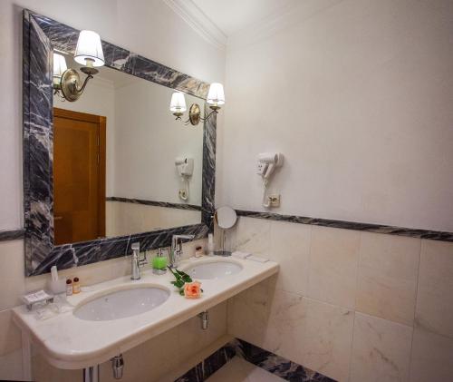 a bathroom with a sink, mirror, and bathtub at Abakan Hotel in Abakan
