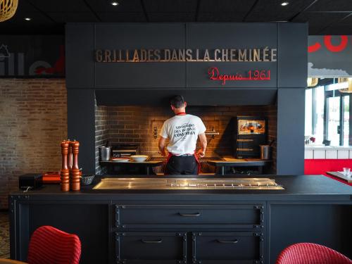 a man standing in a kitchen preparing food at ibis Orange Centre in Orange