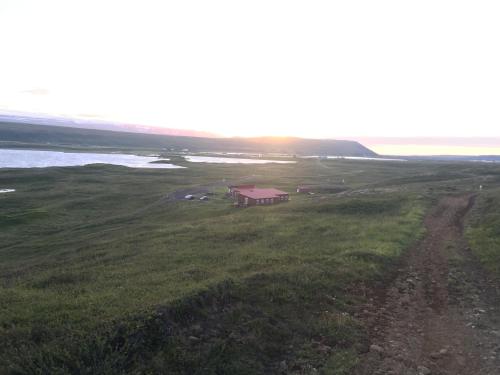 a small house in a field next to the water at Vestmannsvatn Guesthouse in Aðaldalur