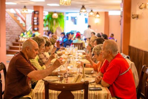 un grupo de personas sentadas en una mesa larga en Hotel Donde Ivan, en Baños